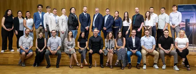 Mintegy harmincöt fős csoportkép egy faburkolatú előadóteremben, a háttérben MVM Smart Future Lab feliratú roll-up; Klein Péter az ülő sor közepén.